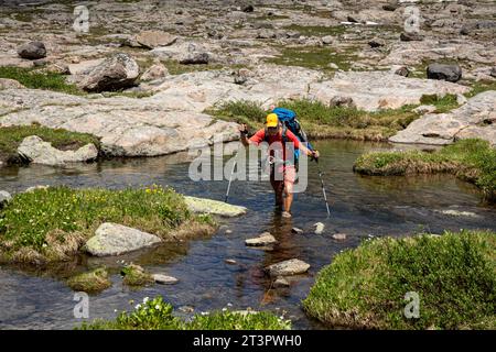 WY05331-00...WYOMING - Hiker keeping his boots dry while crossing Elbow Creek on the Continental Divide Trail in the Wind River Range. Stock Photo