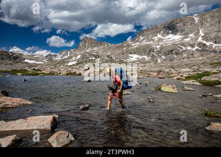 WY05333-00...WYOMING - Hiker keeping his boots dry while crossing Elbow Creek on the Continental Divide Trail in the Wind River Range. Stock Photo