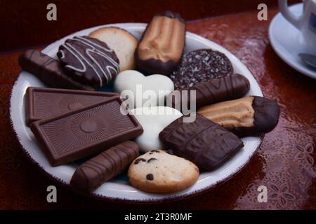 Closeup of a plate of assorted chocolate chip cookies on a tray with cups of coffee Stock Photo