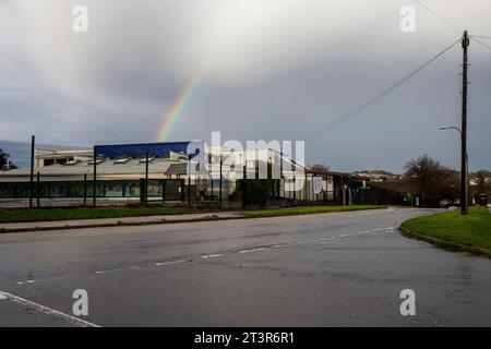 Shiphay school in Torquay from a distance with a rainbow going into a grey cloudy sky Stock Photo