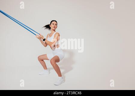 Young slim woman doing sit-ups and using a resistance band Stock Photo