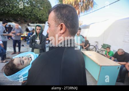 The brother of Al-Jazeera correspondent Wael Al-Dahdouh carries the shrouded body of one of his children who was killed along with his wife the day before in an Israeli strike on the Nuseirat camp, prior to being taken for burial from at Al-Aqsa hospital in Deir Al-Balah, on the southern Gaza Strip, on October 26, 2023. The family of the Al Jazeera journalist were killed in an Israeli strike on Gaza, the Qatar-based network said in a statement on October 25, as war rages between Israel and Hamas. Al Jazeera said the wife and two children of its Arabic-language channel's Gaza correspondent Wael Stock Photo