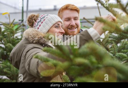 Happy couple selecting Christmas tree at X-mas fair Stock Photo