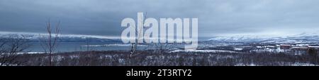 Panoramic view of Torneträsk lake with snowy mountain under a dark cloudy sky in winter in the Abisko National Park Stock Photo