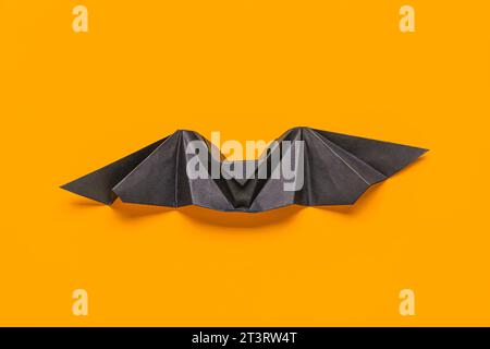 Black origami bat on orange background Stock Photo