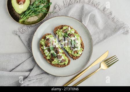 Avocado toast  with mushrooms, feta cheese and microgreens on whole grain bread, top view. Vegetarian food. Vegan menu. Stock Photo