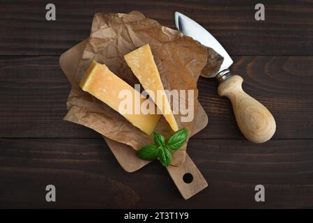 Parmesan cheese on a cutting board with fresh basil on wooden background, top view Stock Photo
