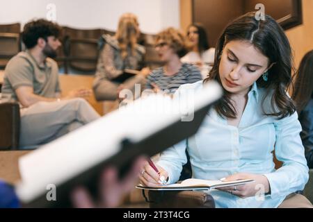 Male holding notebook, close up. Focus on brunette girl writing new business ideas in a notebook Stock Photo