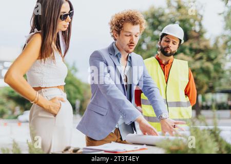 A team of architects, engineers, and designers discussing project details and sustainable design outdoors. Stock Photo