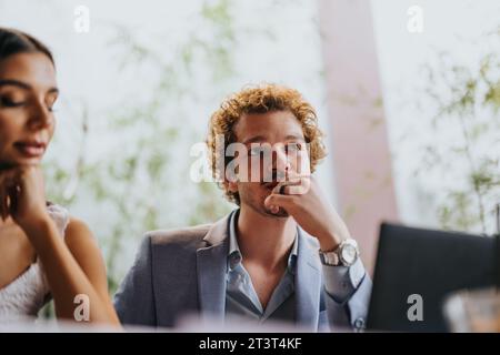 Architects and engineers discuss a blueprint at a coffee bar, collaborating on a building design project and sharing plan details. Stock Photo