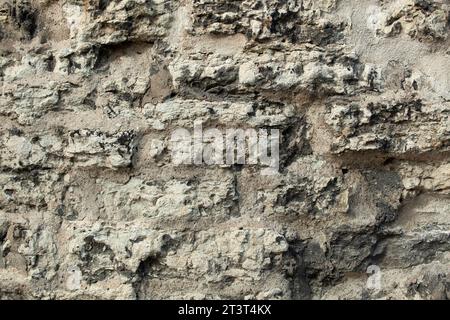 Background uneven concrete wall in holes gray and protruding stones. For decoration. High quality photo Stock Photo