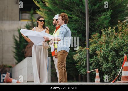 Architects and engineers discuss blueprints on a construction site, ensuring successful and sustainable project management in the city. Stock Photo