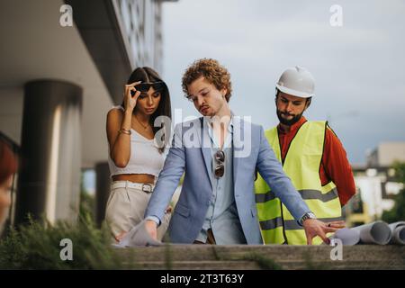 Architects and engineers discussing blueprints, collaborating on construction planning outdoors. Innovative teamwork for project growth and profit. Stock Photo
