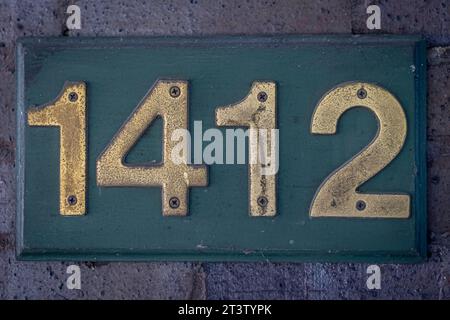 Isolated close up high resolution image of a rustic hose number with red bricks in the background Stock Photo