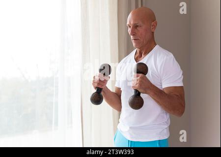 Senior man using fitness dumbbells Stock Photo