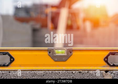 Close-up of the yellow bubble spirit level on top of the block wall on the building site. Bricklayer checking the level of the wall Stock Photo