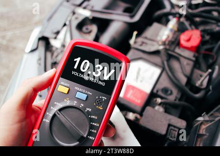 Car voltage problem is too low on black screen of digital multimeter for testing by car technician , Car maintenance service concept Stock Photo