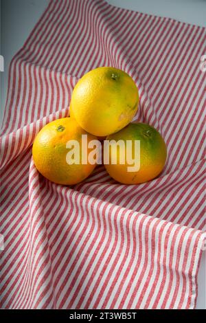 Close-up of oranges on red striped tablecloth background Stock Photo