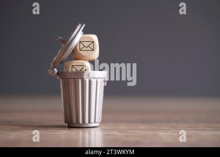 Closeup image of wooden cube with mail icon inside trash can. Junk mail and spam mail concept. Stock Photo