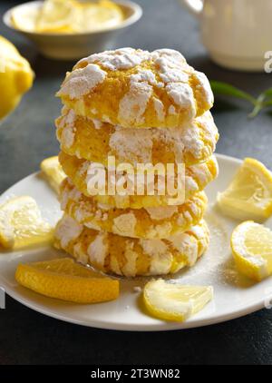 Stack of homemade lemon crinkle cookies on plate over dark stone background. Close up view Stock Photo