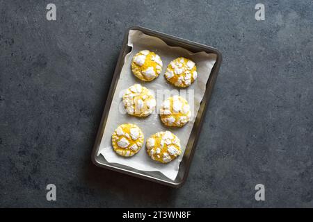 Lemon crinkle cookies on baking sheet over dark stone background with free text space. Top view, flat lay Stock Photo