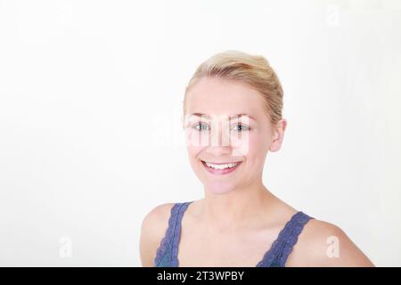 young blonde happy healthy Caucasian model against white background, posing for the camera in summer vest, with angled shoulders Stock Photo