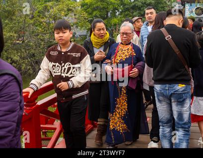 An elderly Vietnamese woman in a traditional colourful ao dai walks with her middle-aged daughter toi Ngoc Son Temple at Tet, or Lunar New Year, Hanoi Stock Photo