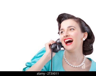 Cheerful vintage style elegant woman having an exciting phone call and gossiping with her friend, she is holding the receiver and smiling Stock Photo