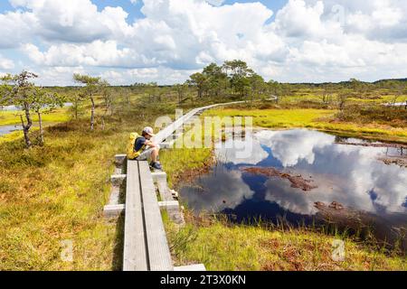 Tourist hiker with a backpack on a Spectacular Kakerdaja bog hiking trail surrounded with small ponds on a beautiful sunny summer day in Estonia Stock Photo