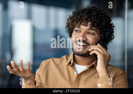 Close up portrait of young businessman, man talking cheerfully and smiling friendly , hispanic man at workplace inside office. Stock Photo