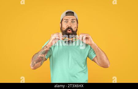 photo of amazed millennial stylish man in sunglasses. millennial stylish man isolated on yellow. millennial stylish man in studio. millennial stylish Stock Photo