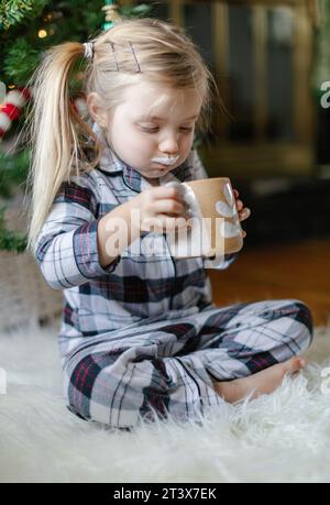 Happy toddler enjoys cocoa, cheeks puffed and milk mustache Stock Photo