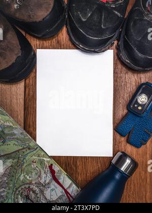 Adventure hiking exploration flat lay mockup with blank paper, headlamp, hiking boots, map, compass Stock Photo