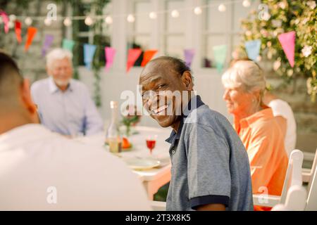 Side view portrait of happy senior man sitting at back yard Stock Photo