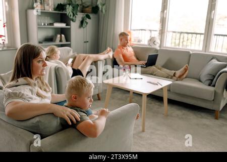 Mother and son with down syndrome watching TV while man and daughter sitting in living room at home Stock Photo
