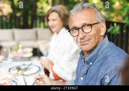 Portrait of smiling retired senior man sitting at dining table Stock Photo