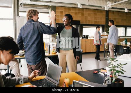 Happy businesswoman giving high-five to colleague at office Stock Photo