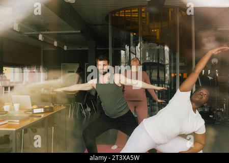 Multiracial colleagues practicing yoga in office Stock Photo