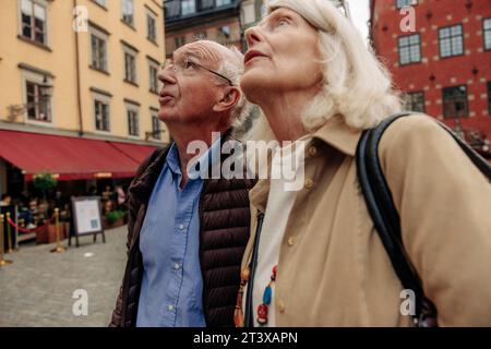 Senior couple looking up while standing together in city Stock Photo