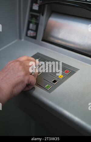 Middle-aged woman using ATM pressing the PIN security on the number pad. Stock Photo