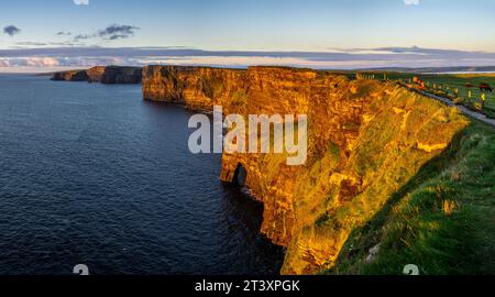 Cliffs of Moher, hiking woman watching the sunset, The Burren, County Clare, Ireland, United Kingdom The Burren, County Clare, Ireland, United Kingdom. Stock Photo