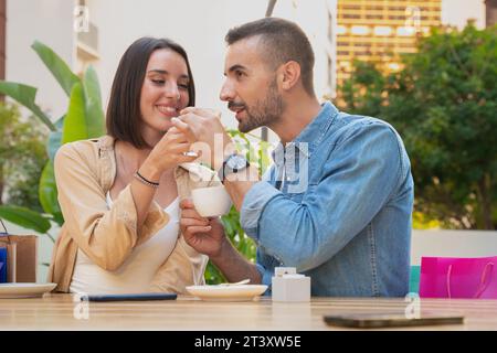 Happy young Caucasian couple taking a break after shopping on the terrace of an outdoor cafe. Stock Photo