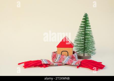 Christmas Tree in a Scarf. Creativity Image of Cold Season. Heating System, Winter is Coming Creative Concept. Model of a House Wearing a Knitted Warm Stock Photo