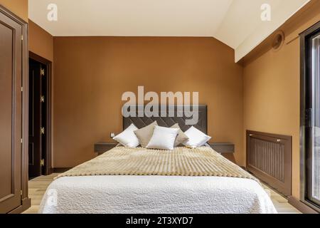 Double bedroom with headboard upholstered in dark brown leather Stock Photo