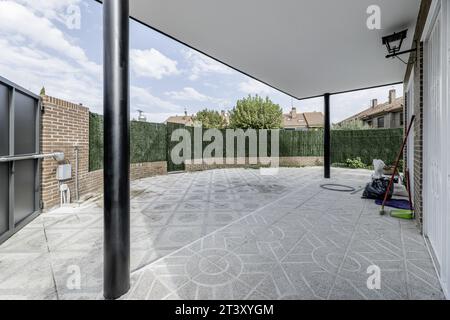 Single-family residential housing plot, party wall with synthetic green hedges, cement porch with black metal posts and terrazzo floor Stock Photo