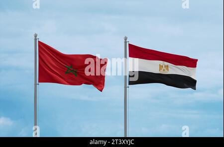 Egypt and Morocco flags waving together on blue cloudy sky, two country relationship concept Stock Photo