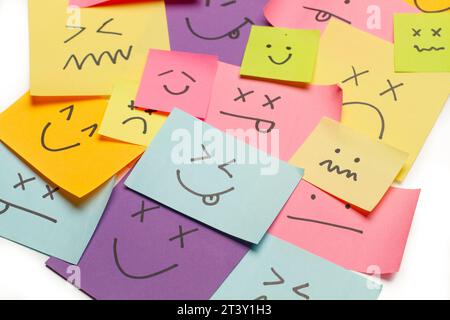 Colored paper notes with drawings of different face emotions on a white background Stock Photo