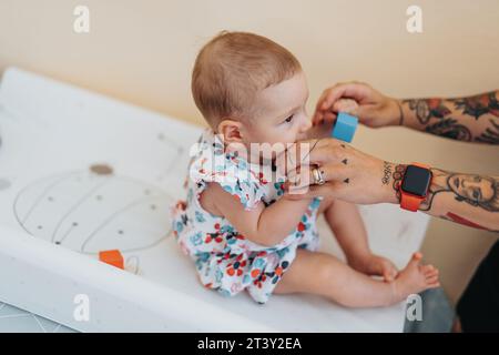 Mom with baby daughter in hospital, waiting for medical check up. Baby girl biting her mom finger. Stock Photo