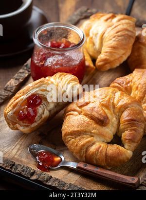 Croissants with strawberry preserves and cup of coffee on rustici wooden tray Stock Photo
