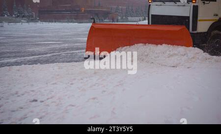 A bucket close-up cleans the sidewalk from snow. The tractor cleans the pavement in winter. Tractor cleaning the road from the snow. Excavator cleans Stock Photo